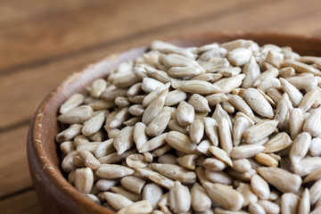 Shelled sunflower seeds in wood bowl on rustic table.