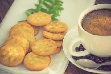 Cup of coffee on a wooden board and biscuits vintage color