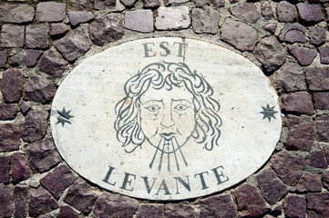 Old wind marker on cobblestone pavement
