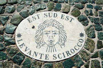 Old wind marker on cobblestone pavement