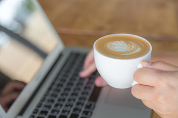 Closeup of business woman hand typing on laptop keyboard and cof