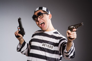 Funny prisoner with weapon isolated on gray