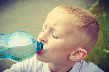 Little thirsty boy child drink water from bottle - obrazy, fototapety, plakaty