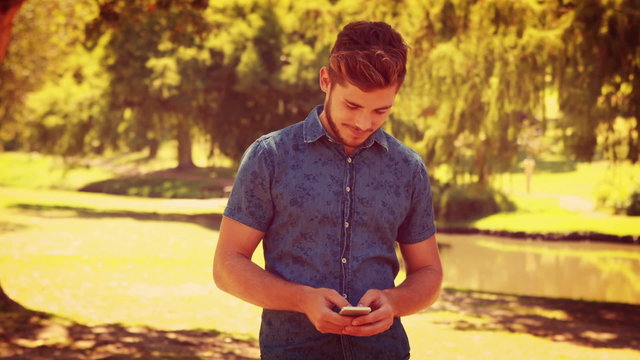 Handsome man texting in the park