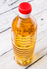 Vegetable cooking oil in a bottle over aged weathered wooden background
