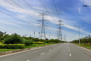  Electricity pylons, power lines and trees silhouetted against a cloudy sky.beside road
