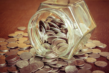 Coins spilling out of a glass bottle with filter effect retro vi