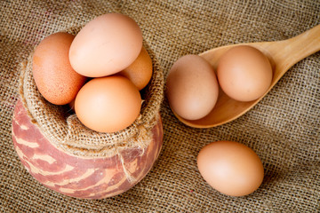 Fresh raw eggs in clay pot put on old sack