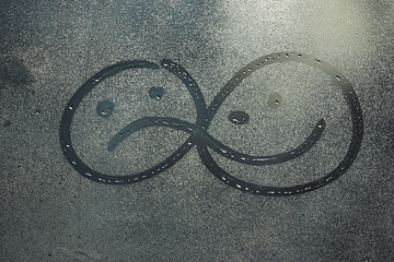 sad and cheerful smiles on wet glass