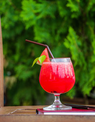 Water melon smoothie on wooden table with notebook and pen