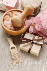 Bowl of sea salt, bar of soap, towels and alstroemeria flower