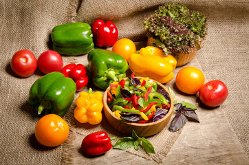 Fototapeta na wymiar salad from bell pepper and basil in a wooden bowl and vegetables