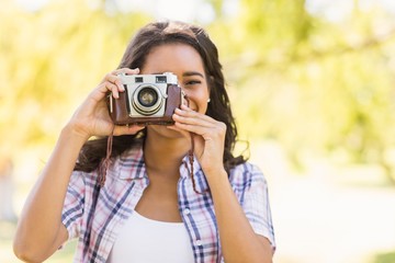 Pretty brunette in the park using retro camera