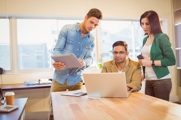 Colleagues using laptop in office