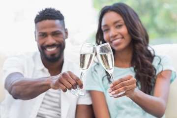 Happy couple on the couch having champagne