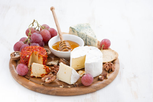 cheeses and snacks on a board on white wooden table