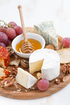 cheeses and snacks on a board, close-up vertical