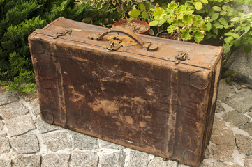 Old used weathered vintage grunge suitcase on stone pavement closeup