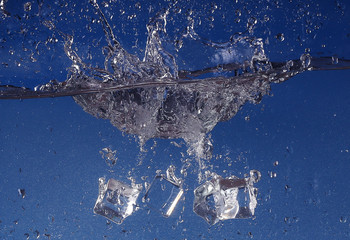 Naklejka na ściany i meble Ice cubes splashing into water, close-up