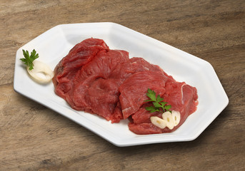 Raw meat selection on wooden cutting board with knife