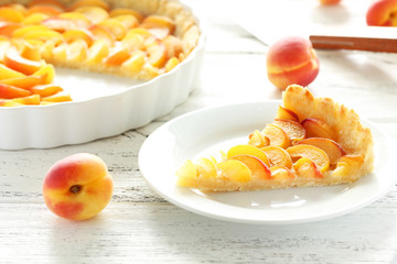 Slice of apricot pie on white wooden background