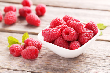 Red raspberry in bowl on a grey wooden background