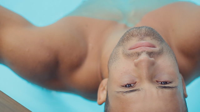 A handsome man with a beard in a swimming trunks in the water at