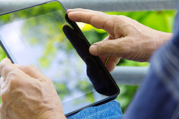 Senior man relaxing at home reading E-book on his tablet.