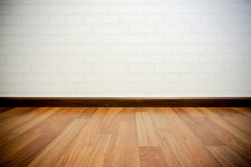 Copyspace background with an empty white bricks wall with a hardwood wooden floor below with large copy space for your text or advertisement