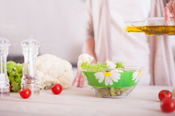 Young woman mixing fresh salad.