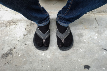 Close up man's lags in jeans with socks and slippers