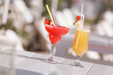 Cocktails garnished with fruit and flowers outdoors. Selective focus