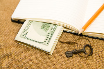 Opened notebook, pencil, key and money on the old tissue