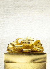Close up Golden present box with big bow at bokeh white blur bac