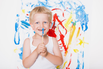 Artist preschool boy painting brush watercolors on a easel