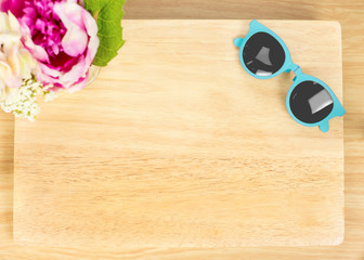 Top view of Blank wooden plate with flower and sunglasses on tab