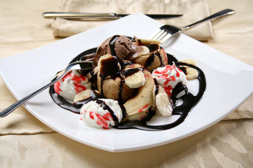 Rolled crepes with scoop of ice cream and chocolate topping on a plate