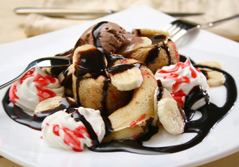 Rolled crepes with scoop of ice cream and chocolate topping on a plate, shallow depth of field