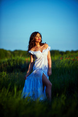 Obraz premium Beautiful woman in a poppy field with flowers