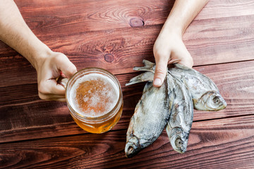 Hand with beer glass and dried fish.
