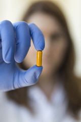 Doctor holding yellow pill capsules
