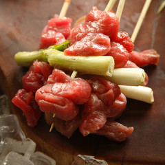 Pieces of meat with onions on chopsticks
