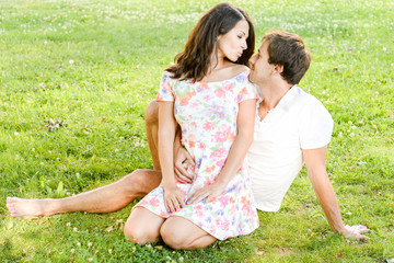 Happy loving pretty young couple outdoors having fun on the sunny day on green grass