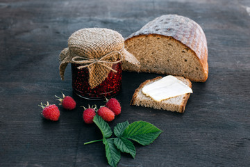 Raspberry jam and bread with butter in a jar on the wooden table Lunch breakfast