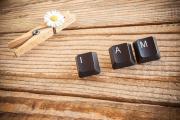 "I am" wrote with keyboard keys on wooden background