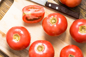 Chopping board, whole tomato, slice and knife top view