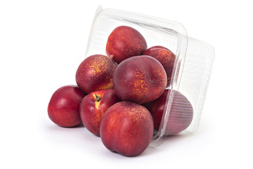 Box or punnet and spilled fresh ripe organic nectarines isolated on white background
