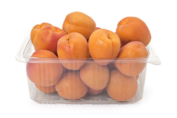 Box or punnet of fresh ripe organic apricots isolated on white background