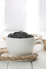 coffee beans and cup on white wood