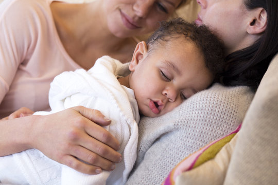 Same sex female couple lying down with their baby son